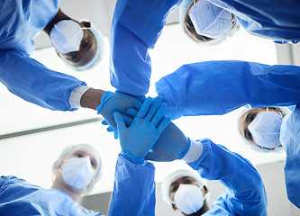 Image showing Doctor, team and hands, surgery and trust in operation theatre together and PPE, partnership and huddle with low angle. Face mask, healthcare and surgeon people, collaboration in hospital and support