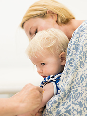 Image showing Child beeing vaccinated by pediatrician in presence of his mother. Preventive vaccination against Diphtheria, whooping cough, tetanus, hepatitis, haemophilus influenzae, pneumococcus, poliomyelitis