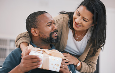 Image showing Birthday, smile and couple with present box, anniversary package or product for love, congratulations or gratitude. Home, lounge and happy woman, black man or marriage people with thank you gift