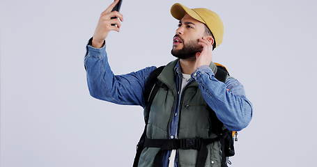 Image showing Phone, service or signal with a hiking man in studio on a gray background searching for reception. Mobile, remote or lost with a young backpacker looking for connection while trekking for adventure