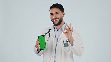 Image showing Doctor, phone green screen and yes hand, success or healthcare support, excellence or ok emoji in studio. Face of medical man for mobile telehealth or services, tracking marker and white background