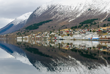 Image showing small town under mountains that are reflected in the sea