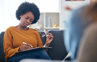 Image showing Therapist on sofa, writing notes with patient, advice and help in psychology, listening and mental health care. Conversation, support and black woman on couch with client, psychologist in counseling.