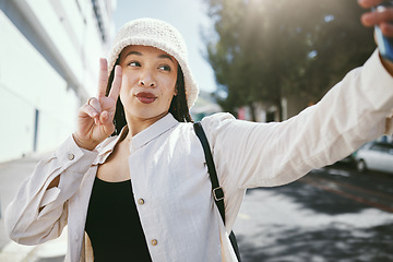 Image showing Woman on city street with selfie, peace sign and travel holiday memory or social media in streetwear. Influencer, streamer or gen z girl with urban fashion, photography and content creation for blog.