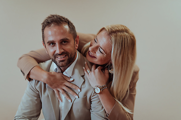 Image showing A business couple posing for a photograph together against a beige backdrop, capturing their professional partnership and creating a timeless image of unity and success.