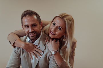 Image showing A business couple posing for a photograph together against a beige backdrop, capturing their professional partnership and creating a timeless image of unity and success.