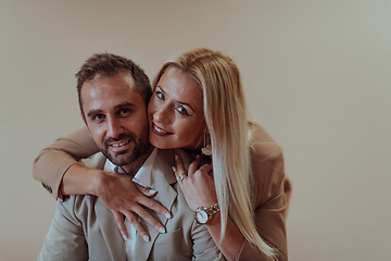 Image showing A business couple posing for a photograph together against a beige backdrop, capturing their professional partnership and creating a timeless image of unity and success.