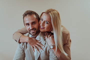 Image showing A business couple posing for a photograph together against a beige backdrop, capturing their professional partnership and creating a timeless image of unity and success.