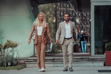 Image showing Modern business couple after a long day's work, walking together towards the comfort of their home, embodying the perfect blend of professional success and personal contentment.