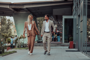 Image showing Modern business couple after a long day's work, walking together towards the comfort of their home, embodying the perfect blend of professional success and personal contentment.