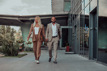 Image showing Modern business couple after a long day's work, walking together towards the comfort of their home, embodying the perfect blend of professional success and personal contentment.