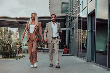 Image showing Modern business couple after a long day's work, walking together towards the comfort of their home, embodying the perfect blend of professional success and personal contentment.