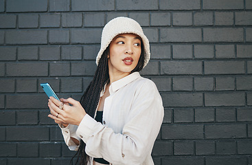 Image showing Woman with phone, brick wall and urban fashion, typing social media post, chat or internet search. Streetwear, gen z girl or online influencer with smartphone for content creation and communication.