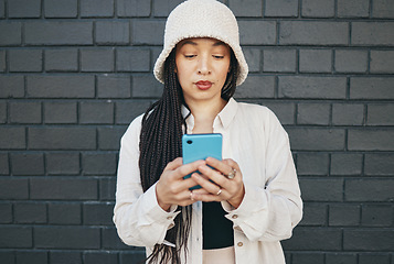 Image showing Girl with phone, brick wall and urban fashion, typing social media post, chat or internet search. Streetwear, gen z girl or online influencer with smartphone for content creation and communication.