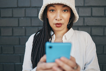 Image showing Portrait of girl with phone, brick wall and urban fashion for social media, typing chat or post online. Streetwear, gen z woman or influencer on smartphone in content creation, communication and tech