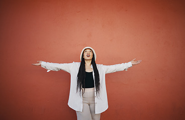 Image showing Excited woman, fashion and arms up for wall and mockup space with urban style and trendy clothing. Freedom, hipster female person and confidence with red background and edgy gen z clothes of a girl