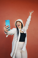 Image showing Selfie, wall and woman with phone in a city for travel, freedom or having fun on orange background. Smartphone, app and lady fashion influencer outdoor on social media, blog podcast content creation