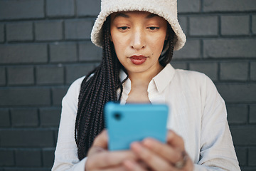 Image showing Girl typing on smartphone, brick wall and urban fashion, for social media chat or or post online. Streetwear, gen z woman or influencer with phone for content creation and communication or technology