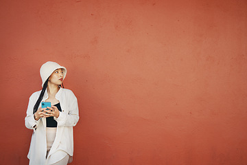 Image showing Thinking, wall and woman with phone in a city for travel, search or location map on orange background. Smartphone, app and lady fashion influencer outdoor on social media, blog, or podcast idea