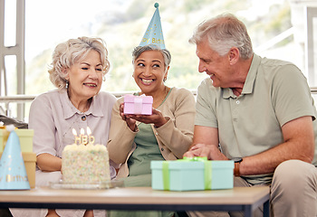 Image showing Birthday, senior friends with cake and gift for celebration in living room, smile and candles in retirement. Happiness, old people and party with dessert, surprise and elderly man with women on sofa.