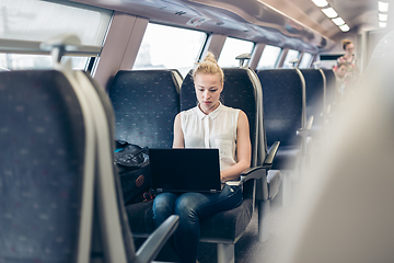 Image showing Woman travelling by train working on laptop.