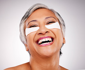 Image showing Mature, happy woman and face with eye patches in skincare, cosmetics or anti aging against a studio background. Senior female person or model smile with pads on eyes for facial treatment or routine