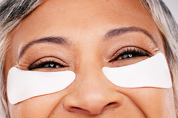 Image showing Closeup, woman and eyes with patches in skincare, cosmetics or anti aging against a studio background. Face of female person or model with eye pads, mask or product for facial treatment or routine