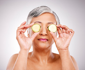 Image showing Senior woman, cucumber and skincare for natural nutrition or beauty against a studio background. Face of mature female person or vegan with vegetable in detox, diet or healthy wellness for spa facial