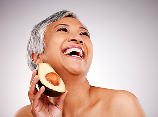 Image showing Happy senior woman, avocado and studio with thinking, results and transformation for skin by white background. Mature female model, fruit and nutrition in diet, beauty and excited for transformation