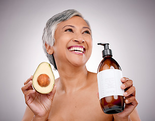 Image showing Senior woman, avocado and studio with smile for bottle, product and ideas for nutrition by white background. Mature female model, fruit and thinking for cleaning, beauty or skincare with organic oil