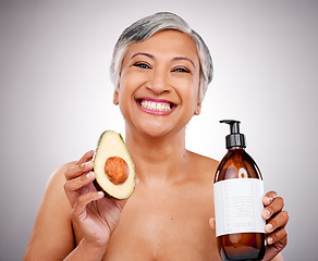 Image showing Mature woman, avocado and studio portrait for bottle, product and promo for nutrition by white background. Senior female model, fruit and excited for cleaning, beauty and skincare with organic oil
