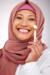 Image showing Facial roller, muslim woman and skin care in studio with quartz for dermatology, cosmetics and glow. Happy mature person portrait with islam hijab, face massage and beauty on a white background