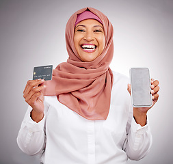 Image showing Muslim woman, portrait and credit card with a phone on a studio background for online shopping. Happy, ecommerce and an Islamic person with a mobile app for banking, finance management and payment