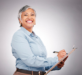 Image showing Portrait, clipboard and mature happy woman writing assessment notes, inspection info or compliance survey. Studio, paperwork and business manager working on report, agenda or list on gray background