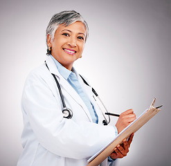 Image showing Planning, notes and portrait of woman or doctor writing feedback, healthcare advice or results. Smile, hospital and mature medical employee or nurse with insurance documents on a studio background