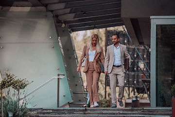 Image showing Modern business couple after a long day's work, walking together towards the comfort of their home, embodying the perfect blend of professional success and personal contentment.