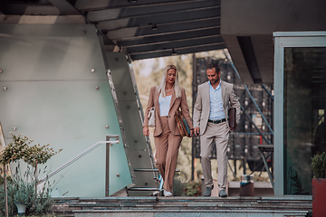 Image showing Modern business couple after a long day's work, walking together towards the comfort of their home, embodying the perfect blend of professional success and personal contentment.