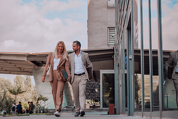 Image showing Modern business couple after a long day's work, walking together towards the comfort of their home, embodying the perfect blend of professional success and personal contentment.