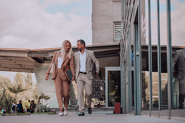 Image showing Modern business couple after a long day's work, walking together towards the comfort of their home, embodying the perfect blend of professional success and personal contentment.