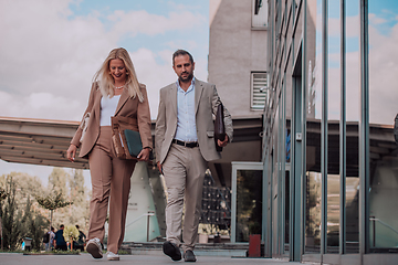 Image showing Modern business couple after a long day's work, walking together towards the comfort of their home, embodying the perfect blend of professional success and personal contentment.