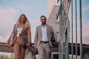 Image showing Modern business couple after a long day's work, walking together towards the comfort of their home, embodying the perfect blend of professional success and personal contentment.