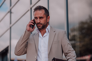 Image showing A businessman using his smartphone outdoors, showcasing the seamless integration of technology and mobility in modern professional life.