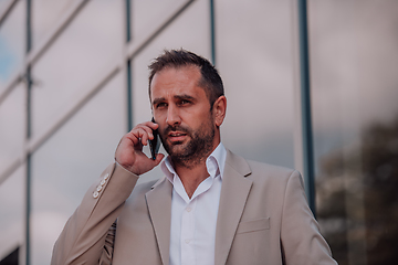 Image showing A businessman using his smartphone outdoors, showcasing the seamless integration of technology and mobility in modern professional life.