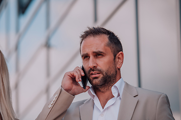 Image showing A businessman using his smartphone outdoors, showcasing the seamless integration of technology and mobility in modern professional life.