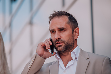 Image showing A businessman using his smartphone outdoors, showcasing the seamless integration of technology and mobility in modern professional life.