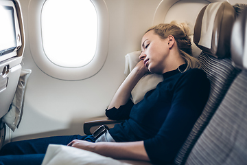 Image showing Tired blonde casual caucasian woman napping on airplane.