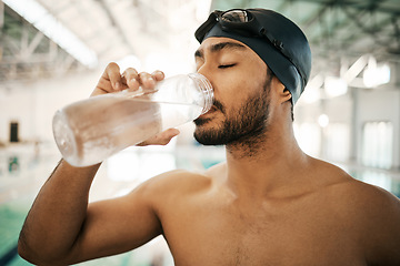 Image showing Man, swimmer and drinking water for hydration, exercise or training workout at indoor swimming pool. Active and thirsty male person or athlete with mineral drink for sustainability, fitness or cardio