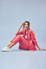 Image showing Portrait, woman and sitting on floor in studio with happiness and makeup for beauty, aesthetic and cosmetics with mockup space. Smile, person and creative clothes on purple background for fashion