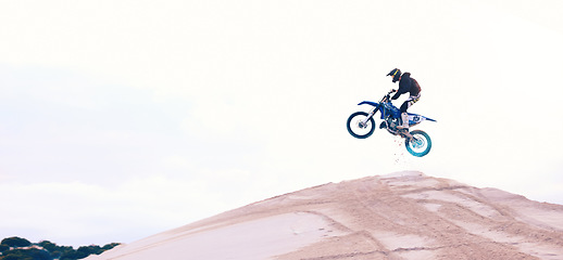 Image showing Sand, jump or athlete driving motorbike for action, adventure or fitness with performance or adrenaline. Speed, air or driver on motorcycle on dunes hill for training, exercise or race challenge