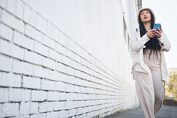 Image showing Woman on street with phone, brick wall and walking in city for travel holiday blog on social media. Influencer, streamer or gen z girl on sidewalk with urban fashion, smartphone and content creation